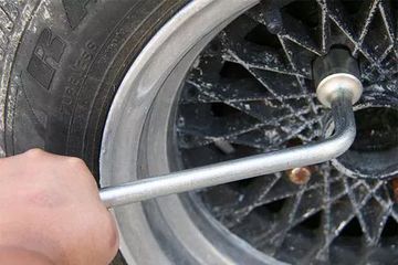 Tháo nắp chụp trục bánh xe và nới các ốc bằng cách quay ngược chiều kim đồng hồ