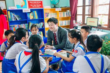 Các em học sinh tiểu học trò chuyện và đọc sách cùng đại diện HVN trong thư viện