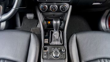 Mazda CX-3 2024 vẫn sử dụng cần số bọc da dạng truyền thống, có thêm phanh tay điện cùng nút bấm Auto Hold